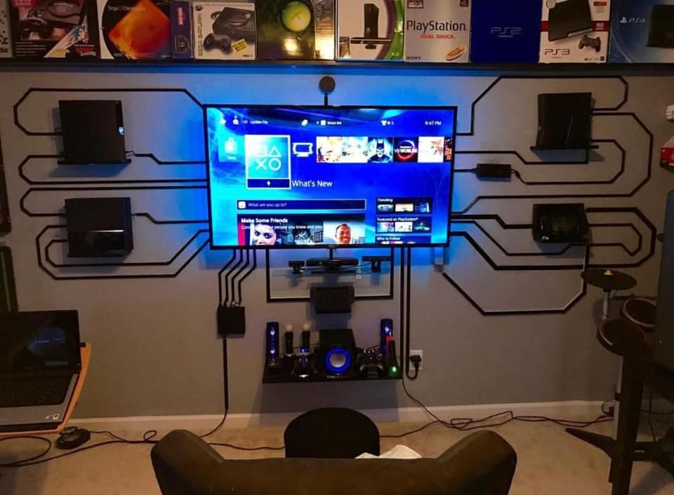 Gaming setup with multiple consoles connected to TV with circuit board design wall